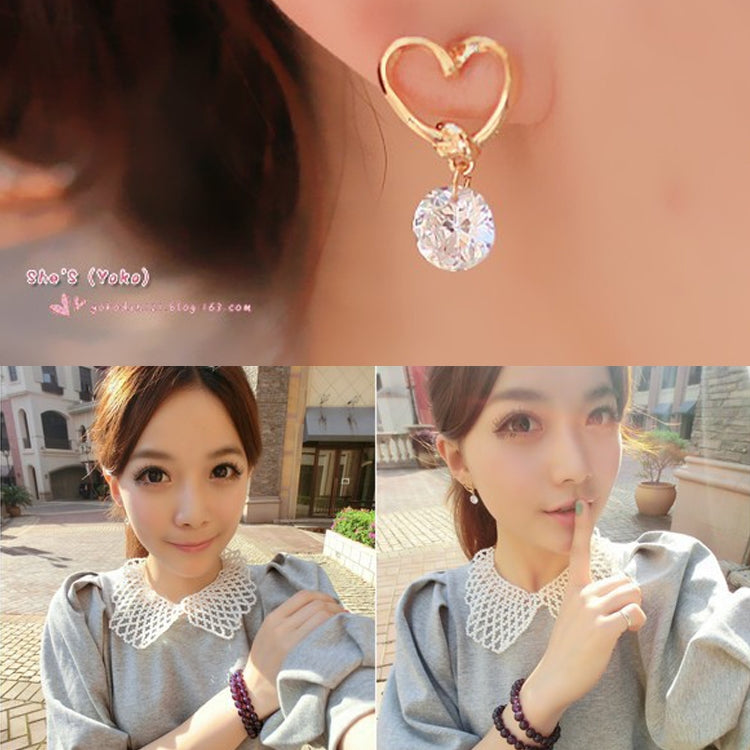 Wearing gold heart drop earrings with dangling clear crystal pendant