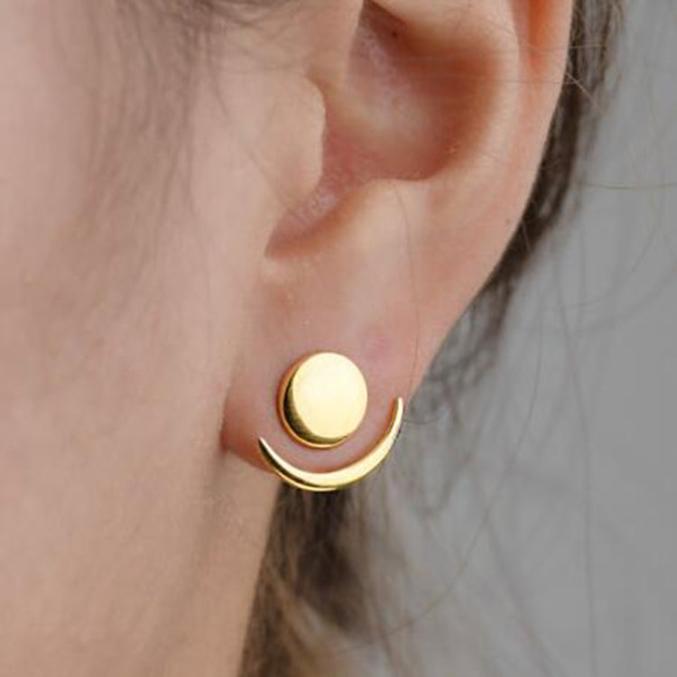Gold crescent moon stud earrings with round disk and curved bar, worn on ear