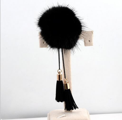Black fur ball chain tassel brooch with gold hardware and dangling black tassels