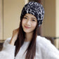 Women’s letter-print turban cap, black with white letters, front view