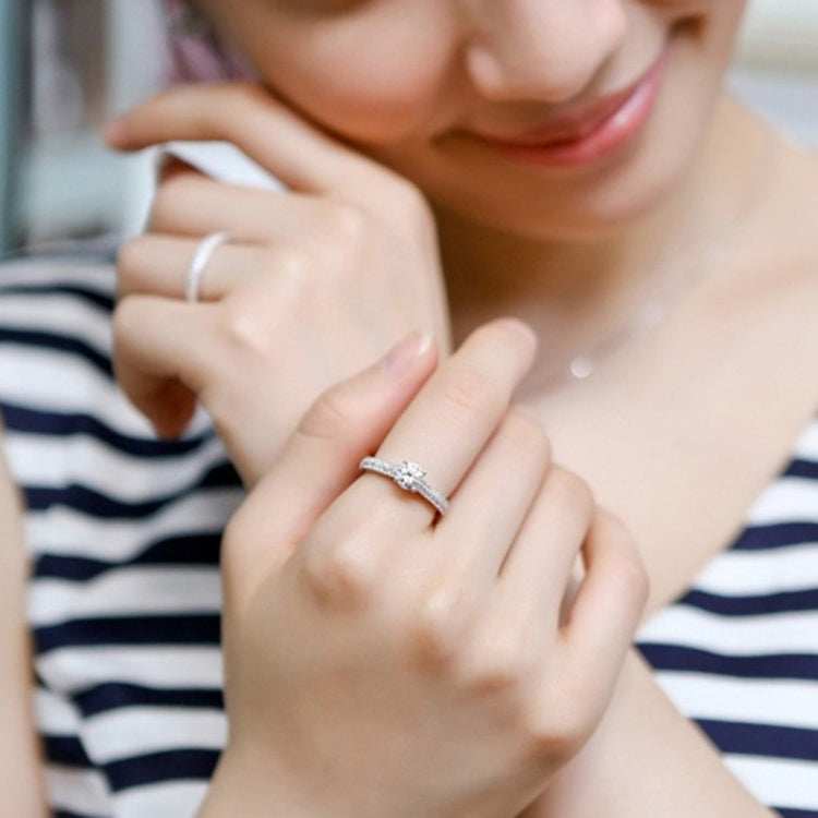 Silver zircon wedding ring on finger with double sparkle band and round center stone