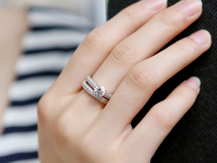 Silver double zircon wedding ring on hand, round center stone and glittering bands