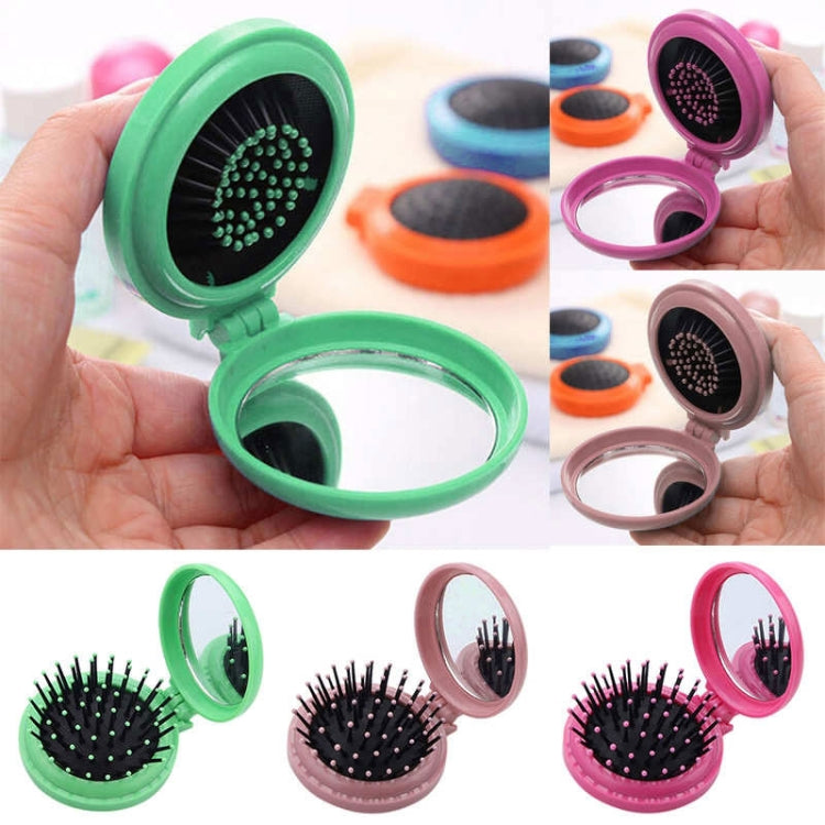 Hand-held green folding pocket hair brush with open round spiked pad