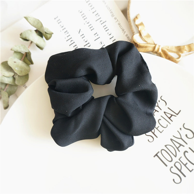 Black fabric scrunchie hair tie with large ruffled loop, seamless stretch design