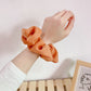 Orange fabric scrunchie hair tie on wrist, large gathered ruffle loop for ponytail