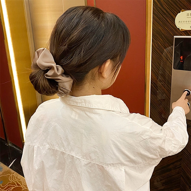 Beige fabric scrunchie hair tie holding a low ponytail on the back of hair
