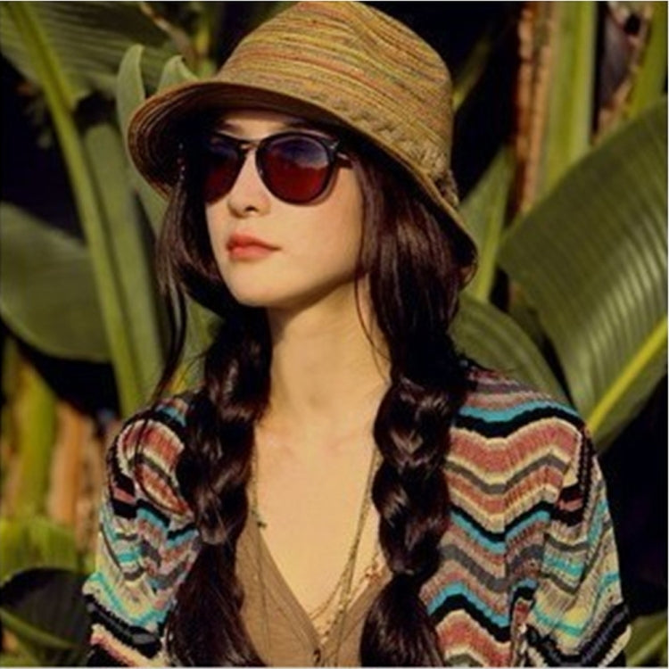 Striped straw topee hat worn with sunglasses and a colorful patterned top