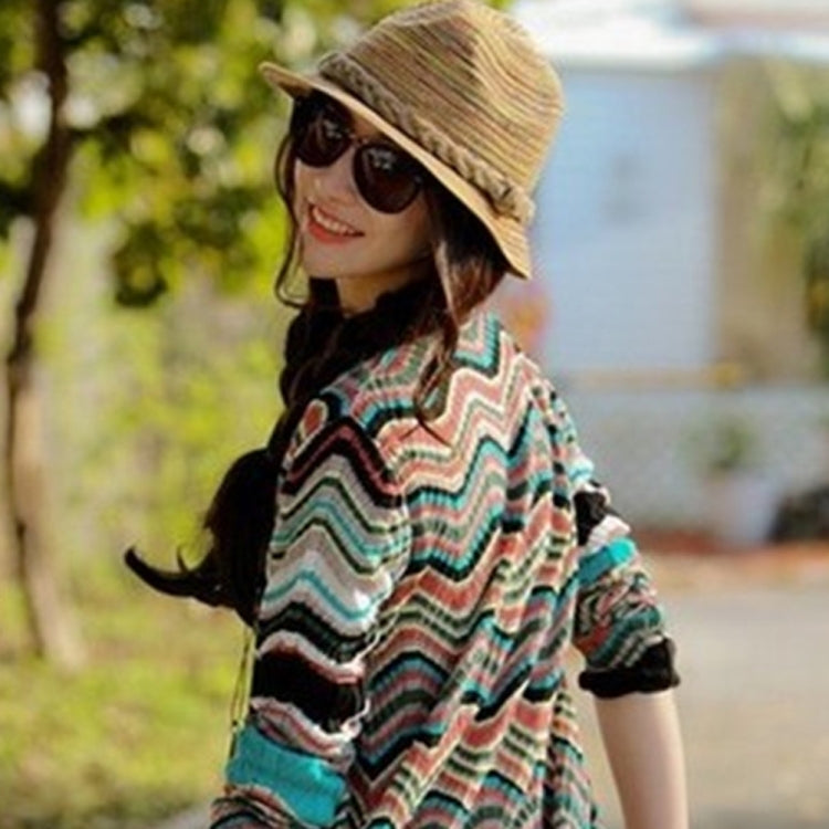 Striped straw foldable hat on a person in a colorful striped blouse