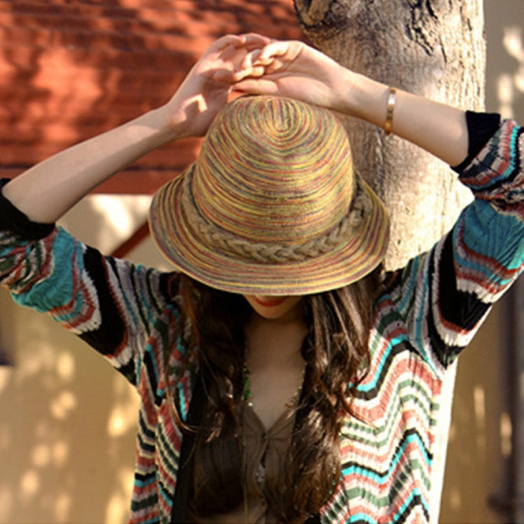 Striped straw topee hat being held up by a person, wide curved brim visible