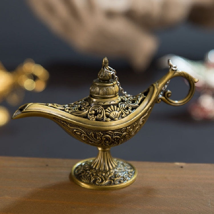 Bronze-gold metal wish lamp with ornate carvings and curled handle