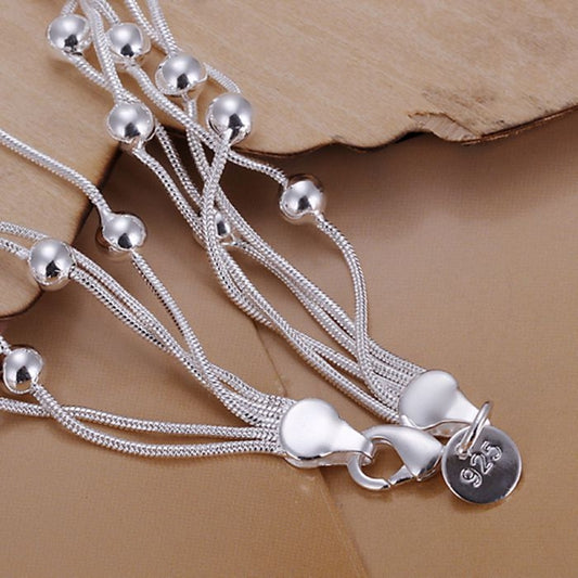 Silver plated bracelet detail: layered cords with spherical beads and round 925 tag charm