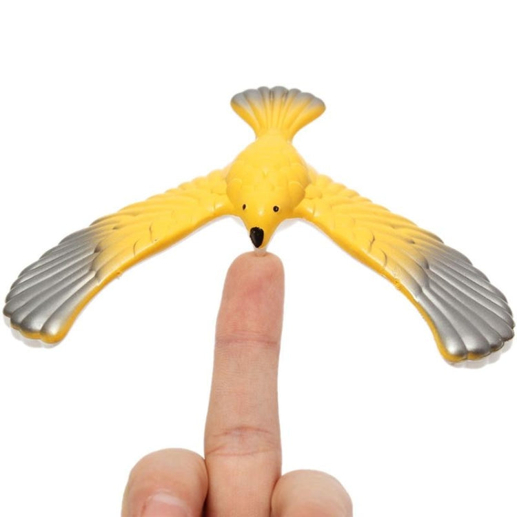 Yellow and gray eagle balance bird toy held by fingertip for balance