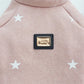Pink pet sweater close-up with star print and front logo patch on the chest
