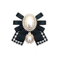 Black and white patterned ribbon bow brooch with oval pearl centers and rhinestone edges