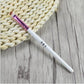 Single eyebrow brush with angled bristles, white handle and purple clear ferrule