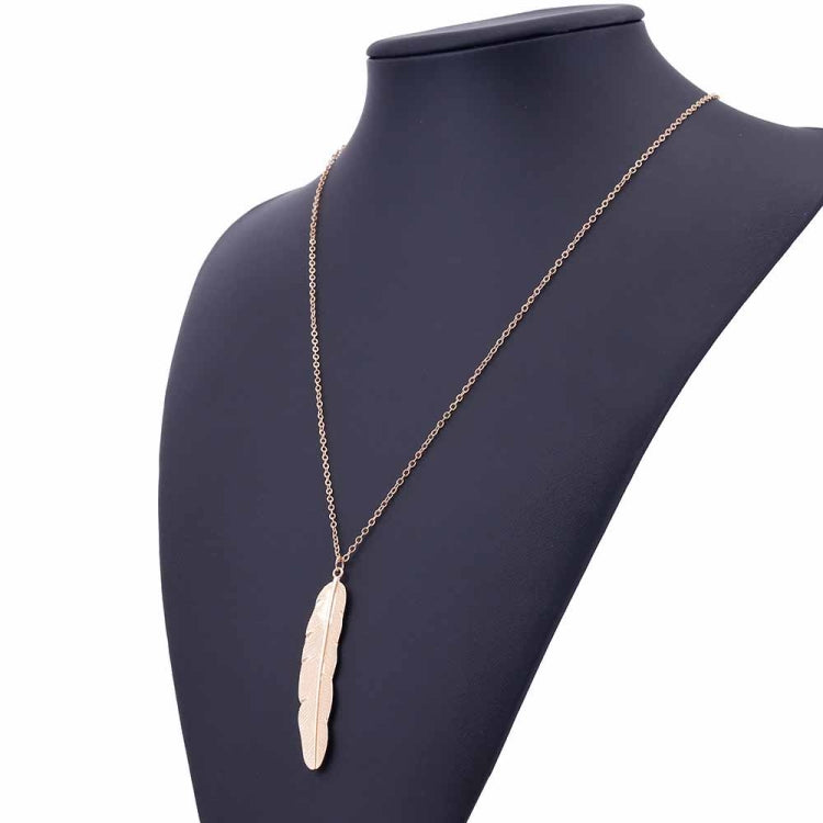 Gold long feather pendant necklace on mannequin, angled view