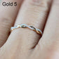 Twist-style cubic zirconia ring on finger, gold-toned metal with small round stones.