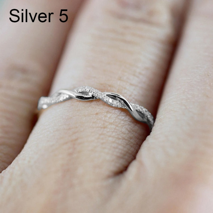 Silver twist cubic zirconia ring on finger, oval stones in curved pattern