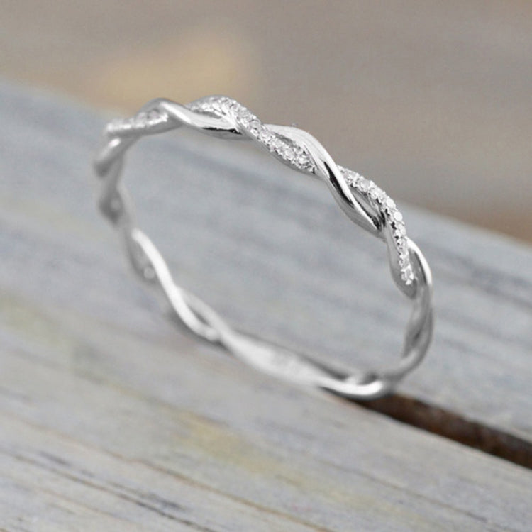 Twist-style cubic zirconia ring, side view, silver-toned metal with sparkling stones.