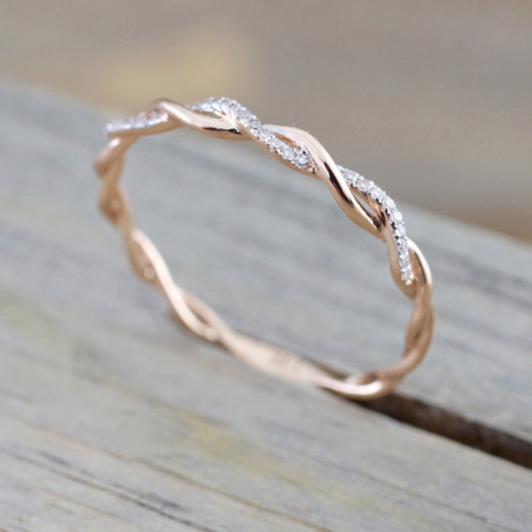 Rose gold twist cubic zirconia ring, side view on wooden surface