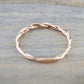 Rose gold twist band cubic zirconia ring, top view on wooden surface