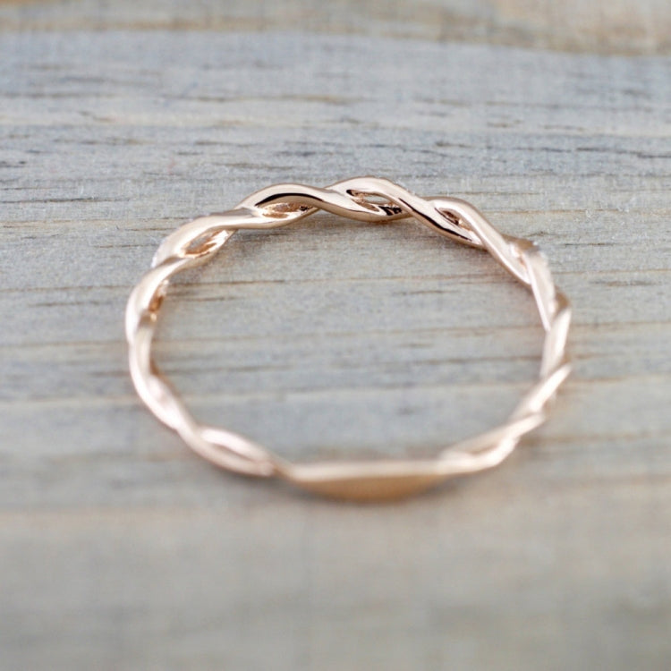Rose gold twist band cubic zirconia ring, top view on wooden surface