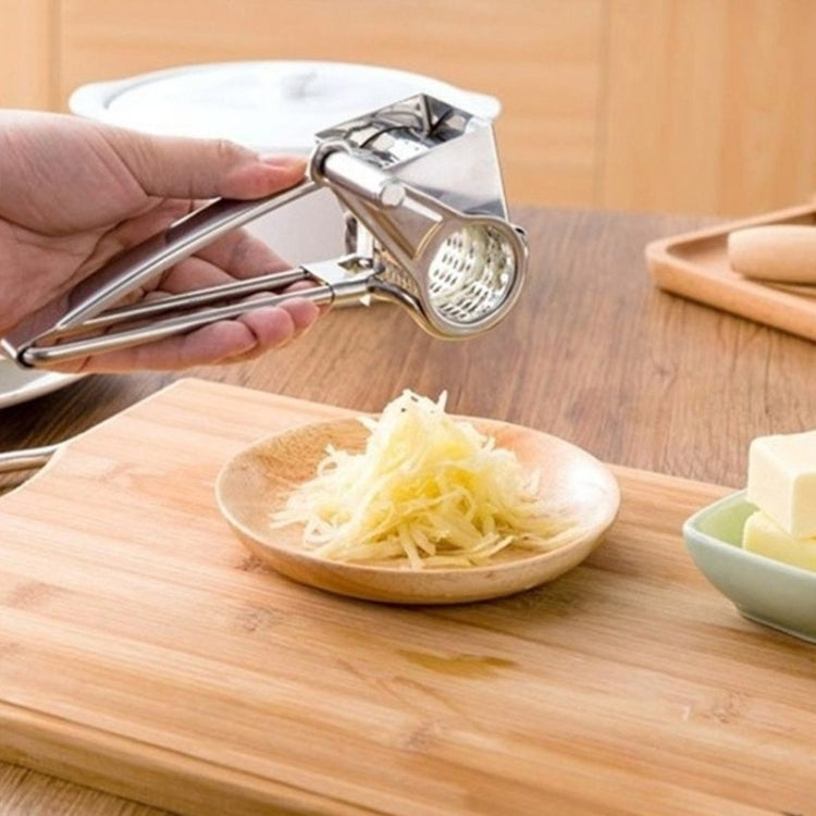 Hand-held stainless rotary cheese grater on a cutting board with shredded cheese