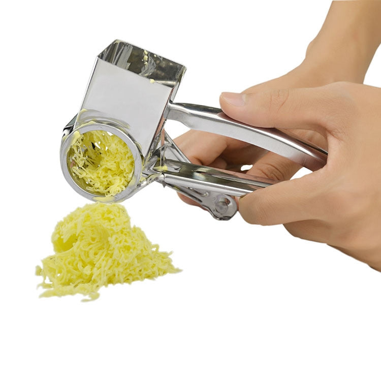 Stainless steel hand-crank rotary cheese grater spilling shredded cheese from the chute