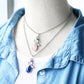 Layered silver necklaces with angel wing pendants and pink, blue, and purple stones