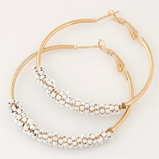 Gold hoop earrings with layered white beaded strands, angled view