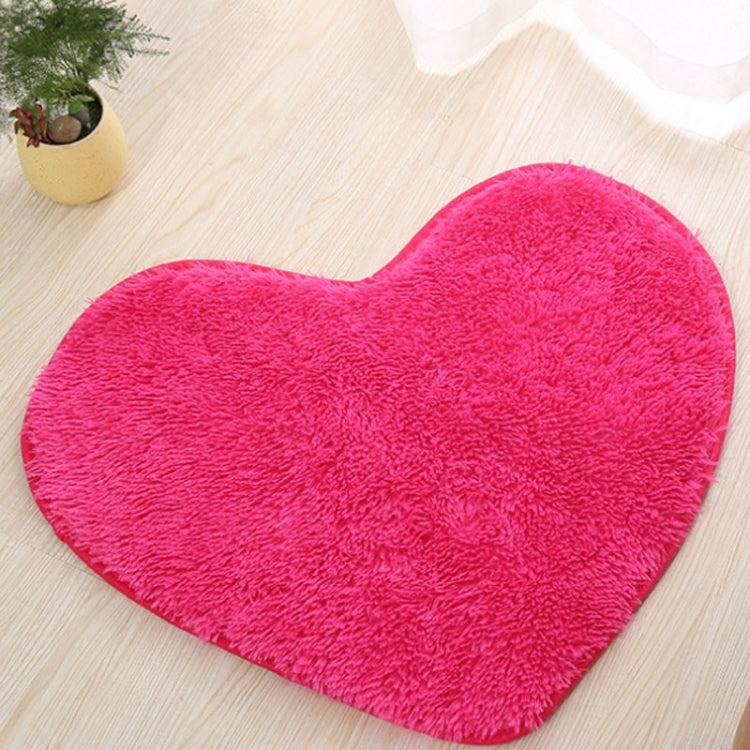 Bright pink heart-shaped bath mat with plush shag pile and non-slip edge binding.