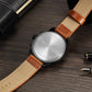 Watch caseback with engraved metal back and two-tone leather straps, tan and dark brown.