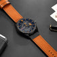 Men's military sports quartz watch on dark surface, black case with blue dial, orange leather strap