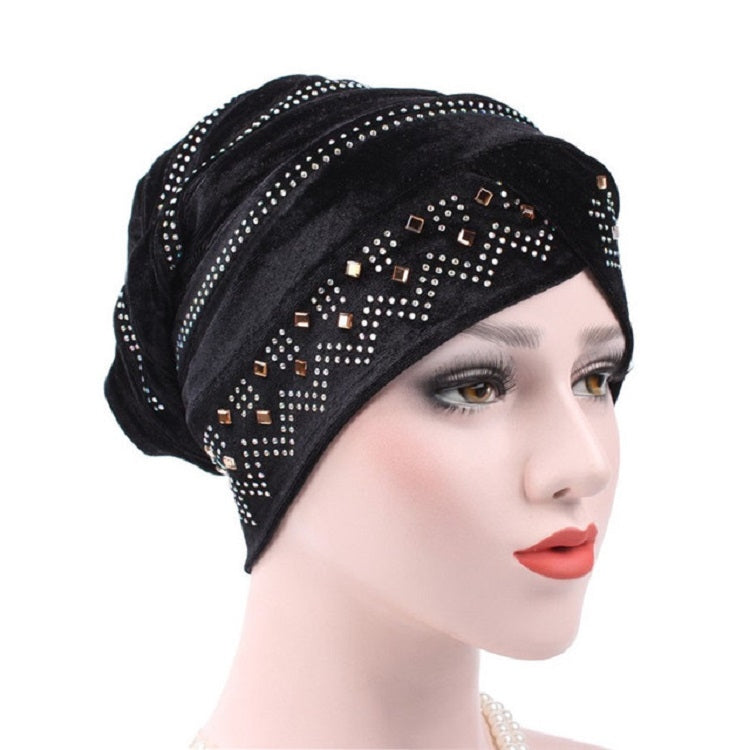 Black pleuche turban hat with rhinestone trim and decorative square accents, angled view