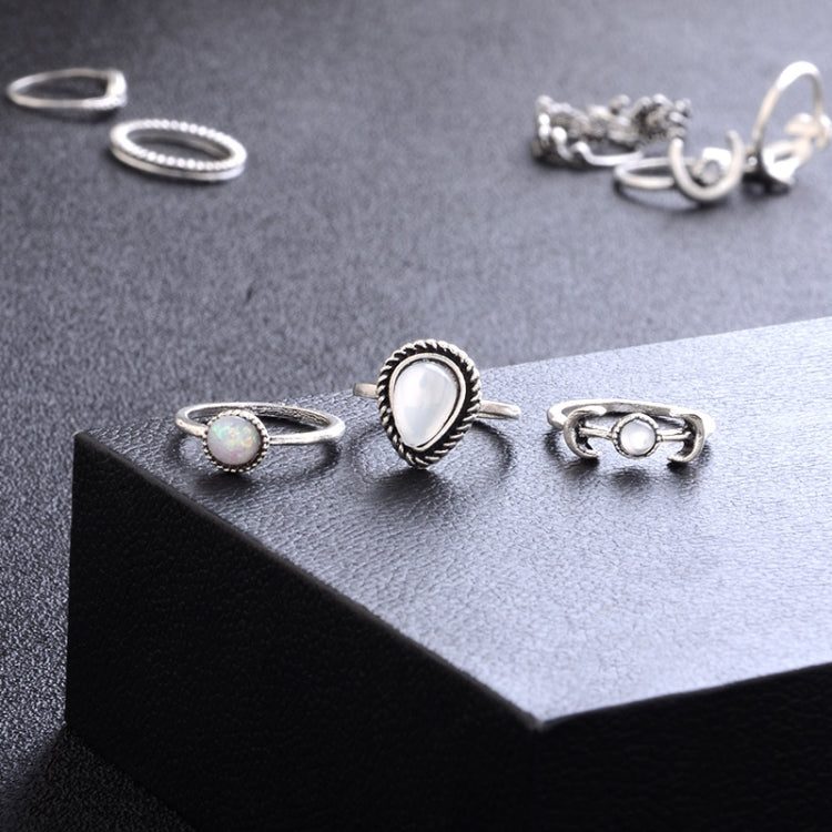Silver-tone ring set on display with moon, opal-like teardrop, and starburst details