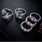 Five adjustable silver-tone star-and-moon rings with clear stones on dark surface