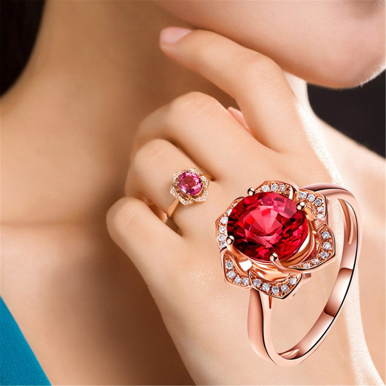 Rose gold flower halo ring with large red oval-cut gemstone and clear stones