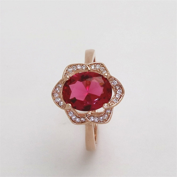 Rose gold open-flower ring with round deep pink gemstone and clear accents