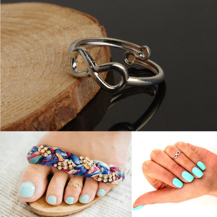 Silver metal infinity toe ring, side view on wooden edge