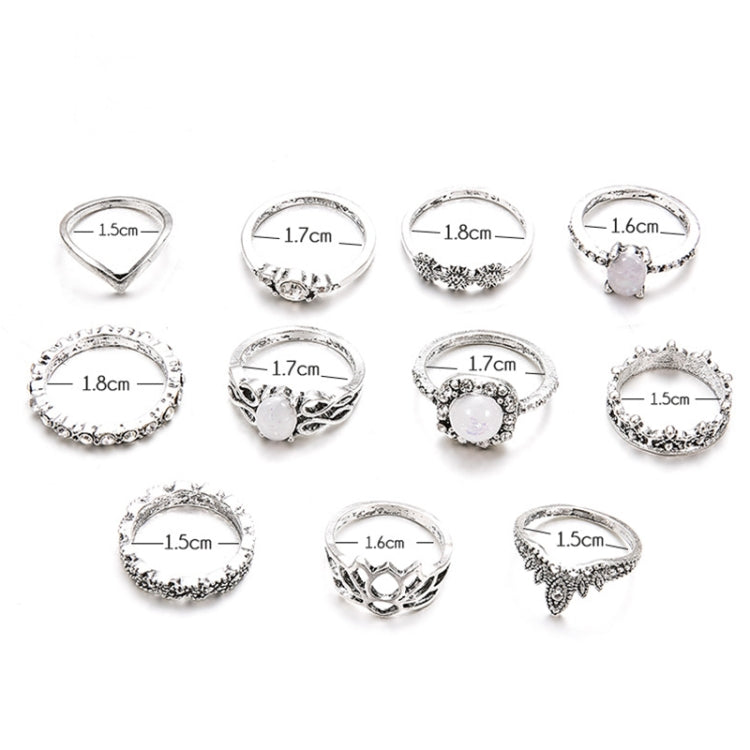 11 silver-tone adjustable rings with opal-style gemstones; top view with size markings