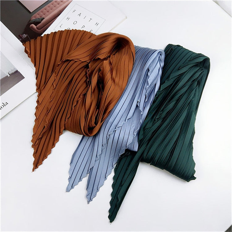 Pleated silk square scarves in brown, light blue, and dark green, tied with striped ends
