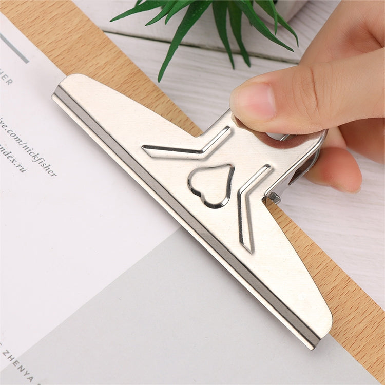 Close-up of hand attaching metal butterfly clip to wooden clipboard