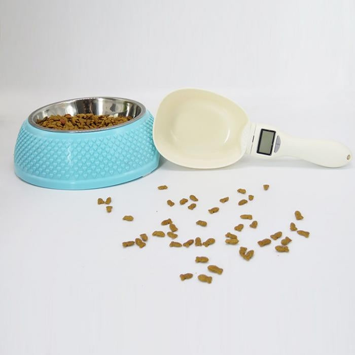 Cream electronic pet food measuring spoon with LCD display near kibble pieces