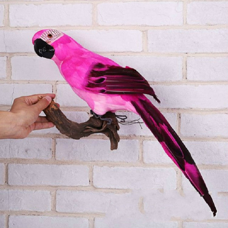 Pink foam parrot decoration with black wing tips and long tail, perched on a branch