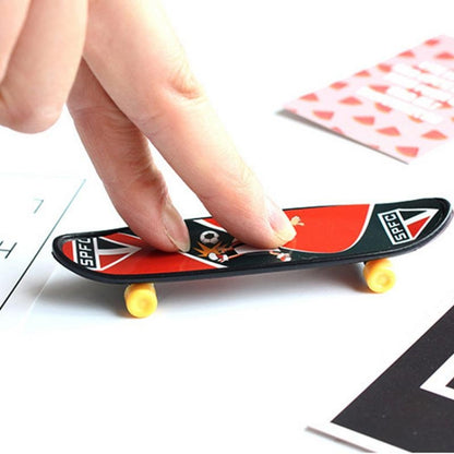 Mini finger skateboard with red and black deck, yellow wheels, held by fingers