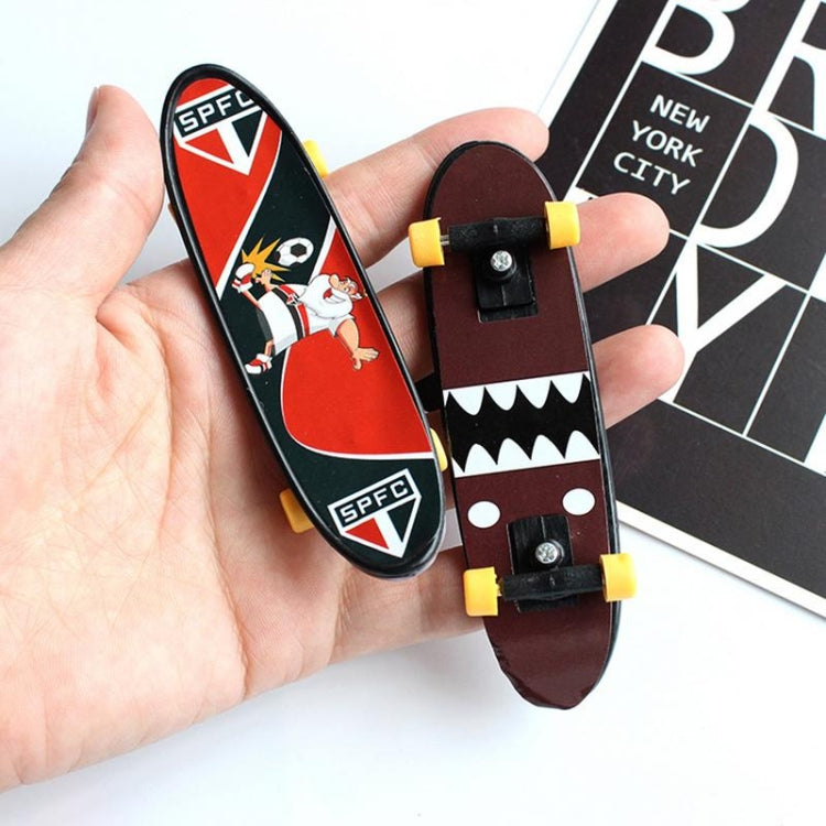 Mini finger skateboard deck with red/black graphics and yellow wheels in a hand