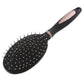 Close view of black paddle hair brush showing dense silver pins on the oval pad surface.