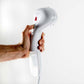 White handheld clothes steamer held in a person’s hand with steam nozzle