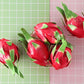 Cluster of red dragon fruit ornaments with green leaves, grouped for display