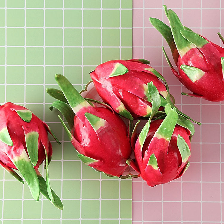 Cluster of red dragon fruit ornaments with green leaves, grouped for display